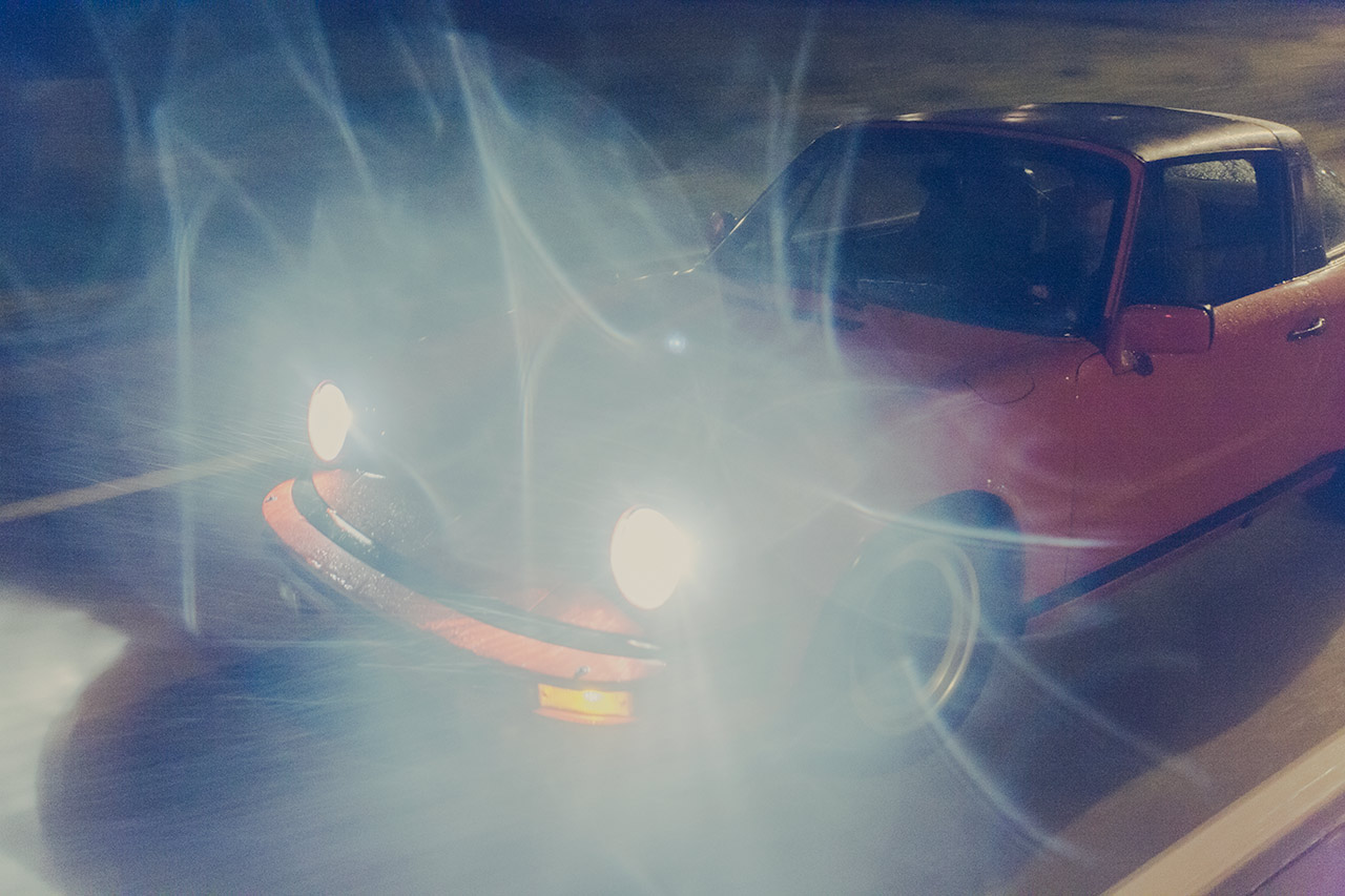 1982 Porsche 911 Targa in guards red driving on a rainy night