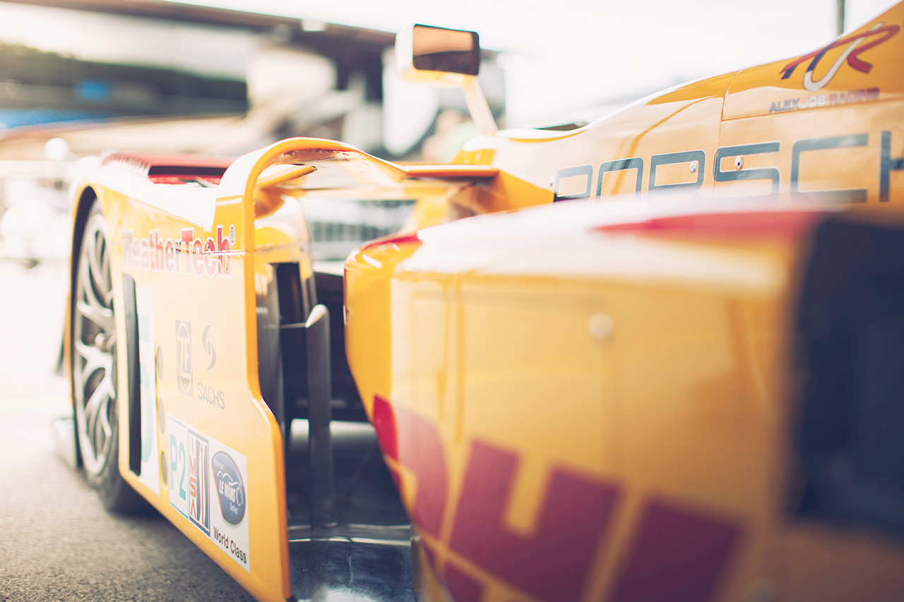 Porsche RS Spyder P2 race car wrapped in DHL livery resting in the paddock between stints